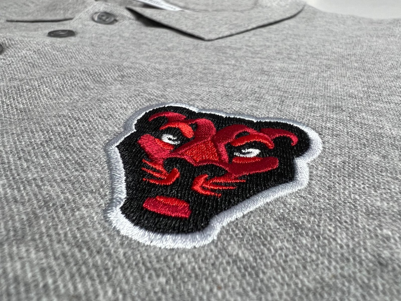 Geborduurd embleem op grijze polo